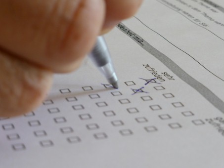 Eine Hand hält einen Stift zum Ausfüllen eines Fragebogens